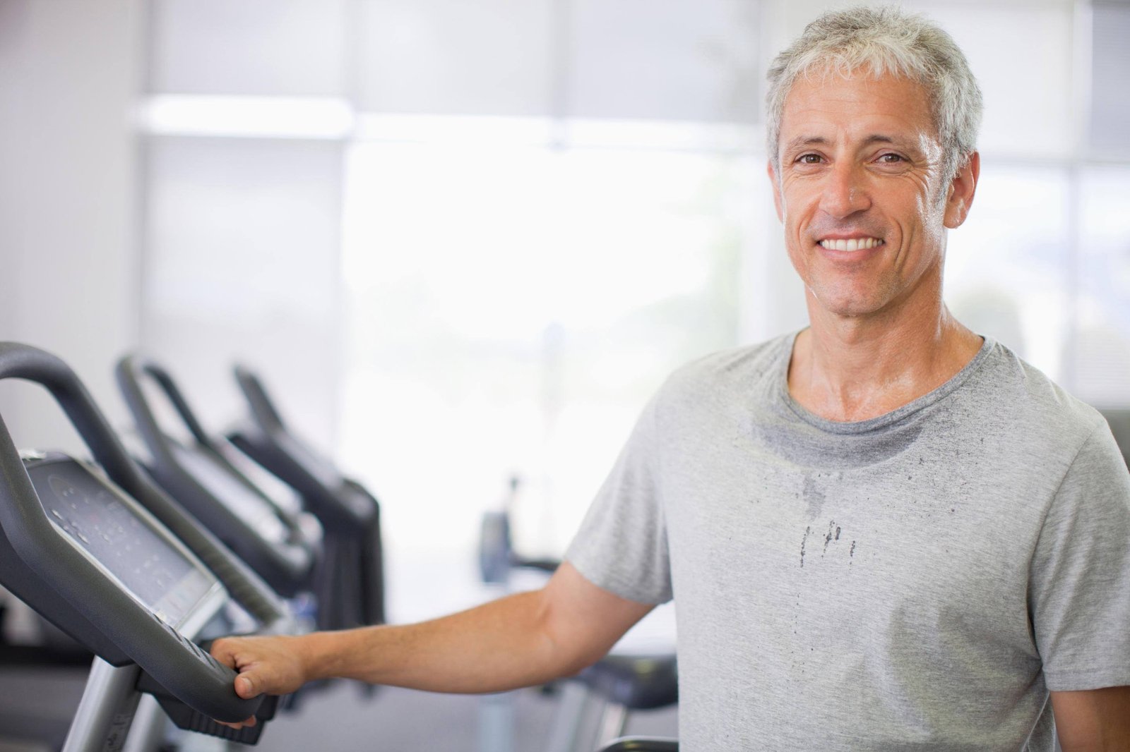 Portrait of smiling man on treadmill in gymnasium